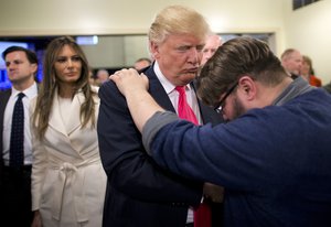 In this Jan. 31, 2016, file photo, Pastor Joshua Nink, right, prays for Republican presidential candidate Donald Trump, as wife, Melania, left, watches after a Sunday service at First Christian Church, in Council Bluffs, Iowa.