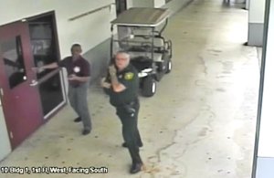 This Feb. 14, 2018 frame from security video provided by the Broward County Sheriff's Office shows deputy Scot Peterson, right, outside Marjory Stoneman Douglas High School in Parkland, Fla.