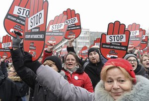 People raise placards reading: Stop Tightening Anti-Abortion Law, as they protest against efforts by the nation's conservative leaders to tighten Poland's already restrictive abortion law, in front of the parliament in Warsaw, Poland, Friday, March 23, 2018.