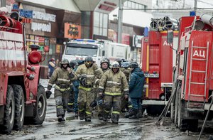 A group of firefighters walk near the scene of the multi-story shopping center after a fire, in the Siberian city of Kemerovo, Russia