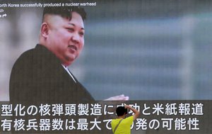 A man takes a photo of a TV news program showing an image of North Korean leader Kim Jong Un while reporting North Korea's rocket launch in Tokyo, Wednesday, Aug. 9, 2017.