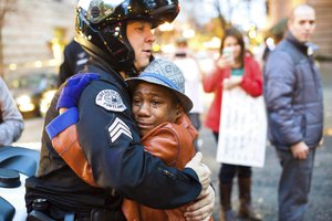 In this Nov. 25, 2014, file photo provided by Johnny Nguyen, Portland police Sgt. Bret Barnum, left, and Devonte Hart, 12, hug at a rally in Portland, Ore., where people had gathered in support of the protests in Ferguson, Mo.