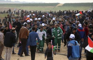 Palestinian medics carry a wounded man who was shot by Israeli troops during a demonstration near the Gaza Strip border with Israel, in eastern Gaza City, Friday, March 30, 2018.