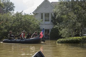 File - Marines with Charlie Company, 4th Reconnaissance Battalion, 4th Marine Division, Marine Forces Reserve, along with a member of the Texas Highway Patrol and Texas State Guard, patrol past a flooded house in the aftermath of Hurricane Harvey, Houston, Texas, Aug. 31, 2017.