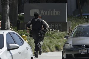 Officers run toward a YouTube office in San Bruno, Calif., Tuesday, April 3, 2018. (AP Photo/Jeff Chiu)