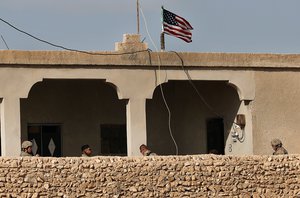 In this Thursday, March 29, 2018 file photo, U.S. soldiers, left, sit in a house turned into an outpost on a road leading to the tense front line between U.S-backed Syrian Manbij Military Council fighters and Turkish-backed fighters, at Halawanji village, north of Manbij town, Syria. President Donald Trump expects to decide "very quickly" whether to remove U.S. troops from war-torn Syria, saying their primary mission was to defeat the Islamic State group and "we've almost completed that task."