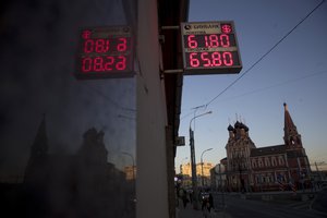 An exchange office screen reflects in a wall as it shows the currency exchange rate of the Russian ruble and U.S. dollar, with the Church of St. Nicholas on Bolvanovka in the background in Moscow, Russia, Wednesday, April 11, 2018.