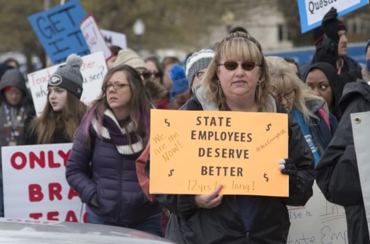 [Photo: An Oklahoman demonstrator holds a sign that reads 