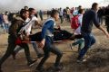 Palestinian protesters evacuate a wounded woman during clashes with Israeli troops along Gaza's border with Israel on Friday.