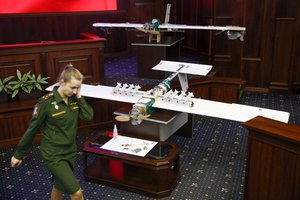 A Russian officer walks next to drones that attacked the Russian air base in Syria and were captured by the Russian military are displayed at a briefing in the Russian Defense Ministry in Moscow, Russia, Thursday, Jan. 11, 2018.