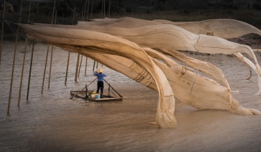 A fisherman checking on his catch in the fishing village of Fujian, China.