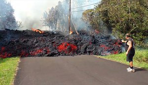 In this photo from video by Scott Wiggers of Apau Hawaii Tours, an unidentified man gets a bit too close to a lava flow advancing down a road in the Leilani Estates subdivision near Pahoa on the island of Hawaii Monday, May 7, 2018.