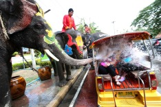 In this Tuesday, April 11, 2017 photo, with assist from its mahouts, elephants blow water from its trunk to tourists on ...