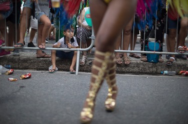 A child watches members of a samba school parading along Copacabana Beach in Rio de Janeiro, Brazil. Musicians and ...