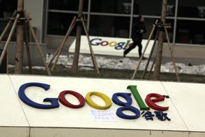 A woman runs past Google logos with a piece of paper which reads "Don't be evil, Don't be emotional" outside the Google China headquarters in Beijing, China, Saturday, Jan. 16, 2010.