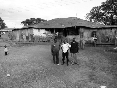 Photographie  – Des membres du Jubilee Club devant Nyumba Kubwa, une des maisons les plus anciennes de Kibera, considérée un temps pour accueillir le musée