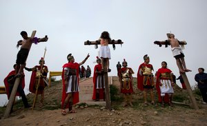 Three devotees hang on crosses in a reenactment of the final procession of Jesus Christ to his crucifixion, at the Villa Litoral calvary, overlooking La Paz, Bolivia, Friday, March 30, 2018.