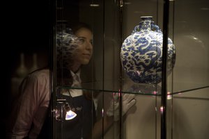 A Sotheby's employee poses for photographs next to a blue and white "Dragon" moon flask of the Qing Dynasty, Qianlong period, at the auction house's premises in London, Friday, Nov. 1, 2013.