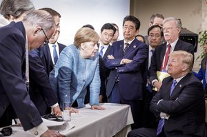 In this photo made available by the German Federal Government, German Chancellor Angela Merkel, center, speaks with U.S. President Donald Trump, seated at right, during the G7 Leaders Summit in La Malbaie, Quebec, Canada, on Saturday, June 9, 2018.