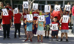 Kids hold up signs during an immigration family separation protest in front of the Sandra Day O'Connor U.S. District Court building, Monday, June 18, 2018, in Phoenix.