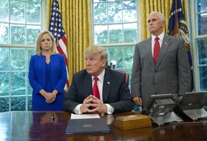 President Donald Trump, center, with Homeland Security Secretary Kirstjen Nielsen, left, and Vice President Mike Pence, right, before signing an executive order to end family separations, during an event in the Oval Office of the White House in Washington, Wednesday, June 20, 2018.