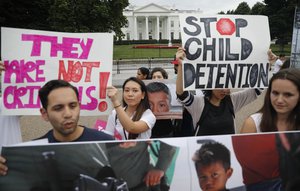 People hold up signs and photographs during a demonstration opposed to President Trump's family separation policy, infront of the White House in Washington, Thursday, June 21, 2018.