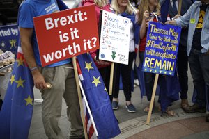 In this photo taken Wednesday, June 20, 2018, anti-Brexit, pro-EU supporters hold placards during a protest near the Houses of Parliament in London.