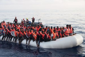 In this photo taken on Thursday, June 21, 2018, migrants on a rubber boat are being rescued by the ship operated by the German NGO Mission Lifeline in the Mediterranean Sea in front of the Libyan coast.