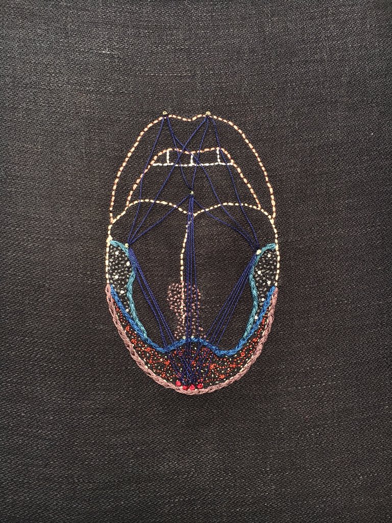 The outline of a tongue embroidered in my own skin tones on black linen. There are myriad stitches in blues, greens, silvers, and reds on the tongue and taught blue lines joining some of the stitches in triangle shapes.