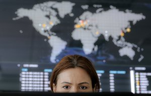 A woman looks at a computer monitor back dropped by a real time cyber attacks world map, at the headquarters of Bitdefender in Bucharest, Romania, Wednesday, June 28, 2017.