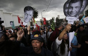 Supporters of Ecuador's former President Rafael Correa hold up images of his face as they protest an attempt to prosecute him, outside the National Assembly in Quito, Ecuador, Thursday, June 14, 2018.