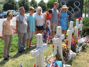 People pause for a moment of silence next to a memorial outside near the Capital Gazette building Thursday, July 5, 2018, in Annapolis, Md., for the five Capital Gazette employees who were killed a week ago in one of the deadliest attacks on journalists in U.S. history.