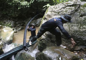 Thai soldiers drag water pipe for bypass water from mountain not get back inside cave where 12 boys and their soccer coach have been trapped since June 23, in Mae Sai, Chiang Rai province, in northern Thailand Saturday, July 7, 2018.