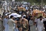 People carry the coffins of the victims of a suicide bombing at an election rally for burial in Peshawar, Pakistan, Wednesday, July 11, 2018.