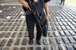 In this March 16, 2013 file photo, an officer of the Prosecutor General's Office guards packages containing cocaine during a media presentation at the airport in Tumaco, Colombia.