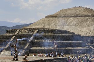 An actor dressed as an Aztec holds the Panamerican Games flame as he is back dropped by the Pyramid of the Sun at the Teotihuacan archeological site, Monday, June 4, 2007.