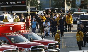 Los Angeles officials escort a woman being evacuated by emergency personnel after a gunman held hostages inside a Trader Joe's store in Los Angeles Saturday, July 21, 2018.