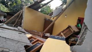 This handout photograph taken on July 29, 2018 and released by the Nusa Tenggara Barat Disaster Mitigation Agency (BPBD) shows an Indonesian man (R) standing among the collapsed ruins of a house following an earthquake in Lombok.