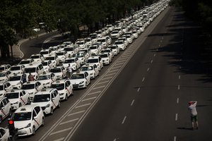 A man takes a photograph of parked taxis blocking the main Castellana avenue in Madrid, Monday, July 30, 2018.