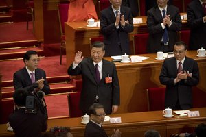 Chinese President Xi Jinping, center, acknowledges applause after being re-appointed head of China's Central Military Commission