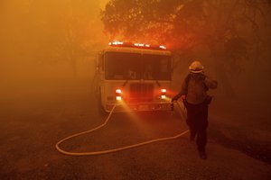 A firefighter rushes to save a home as the River Fire tears through Lakeport, Calif., on Tuesday, July 31, 2018. The residence eventually burned.