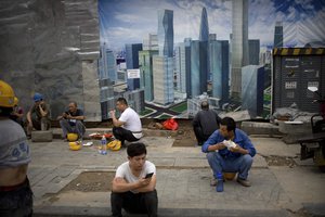 Construction workers take their lunch break outside of a construction site in Beijing, Thursday, July 19, 2018.