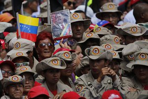 A member of Venezuela's Bolivarian militia holds up an image of President Nicolas Maduro during a march to the Miraflores Presidential Palace in Caracas, Venezuela, Monday, Aug. 6, 2018.