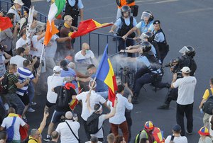 Riot police spray teargas while scuffling with protesters outside the government headquarters, in Bucharest, Romania, Friday, Aug. 10, 2018.