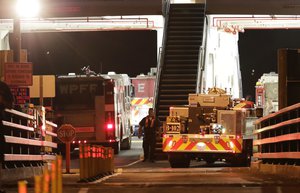 Ferry workers stand by as fire trucks are driven onto a ferry boat headed to Ketron Island, Friday, Aug. 10, 2018, at the ferry terminal in Steilacoom, Wash.