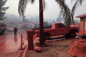 A truck and a street are covered in fire retardant dropped by an air tanker as crews battle a wildfire Friday, Aug. 10, 2018, in Lake Elsinore, Calif.