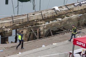 Two police officers work at the scene the day after an oceanside boardwalk collapsed during a nighttime concert in Vigo, Spain, Monday, Aug. 13, 2018.