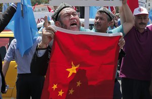 In this file photo taken Sunday, July 5, 2015, Uighurs living in Turkey and Turkish supporters, chant slogans as they hold a Chinese flag before burning it during a protest near China's consulate in Istanbul