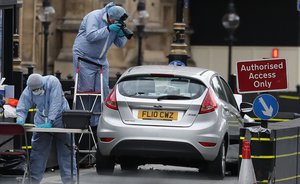 Forensics officers work near the car that crashed into security barriers outside the Houses of Parliament in London, Tuesday, Aug. 14, 2018.