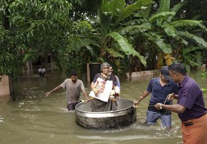 An elderly woman is rescued in a cooking utensil after her home was flooded in Thrissur, Kerala state, India, Thursday, Aug.16, 2018.